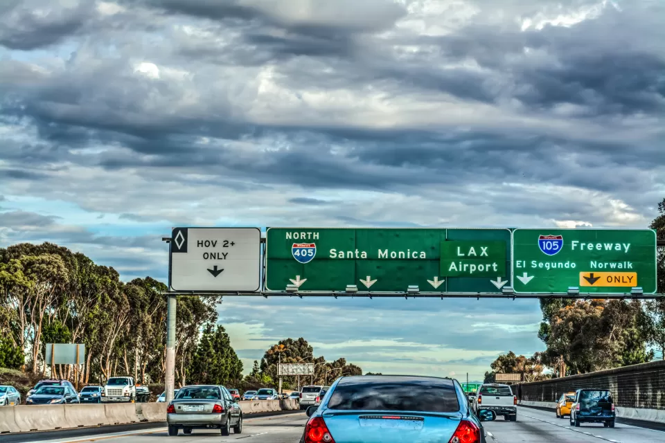 Traffic and green freeway signs with Santa Monica and LAX destinations on Interstate 405 in Los Angeles, California